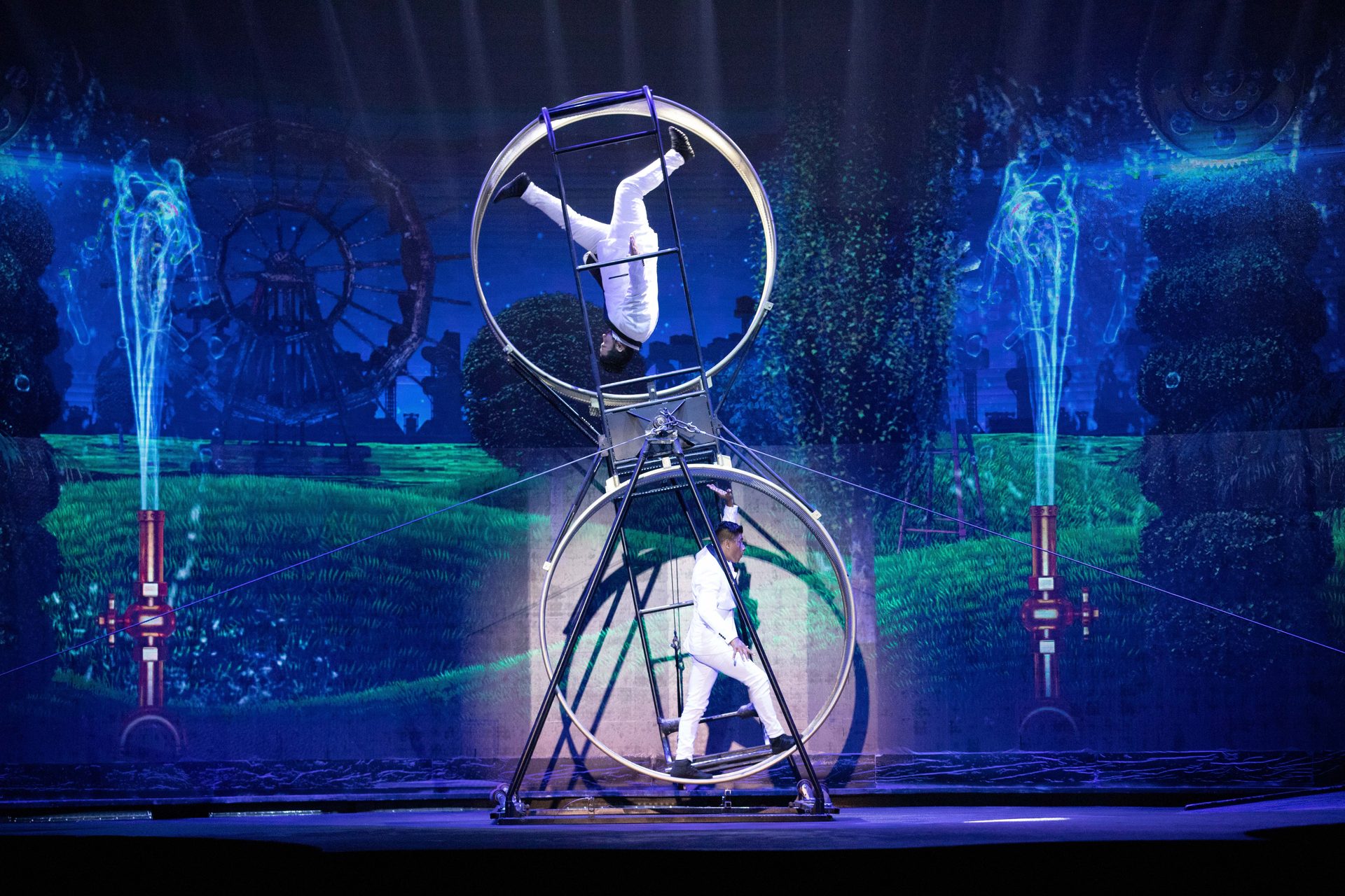 Acrobats performing in large circular wheel apparatus with water effects at WOW Las Vegas
